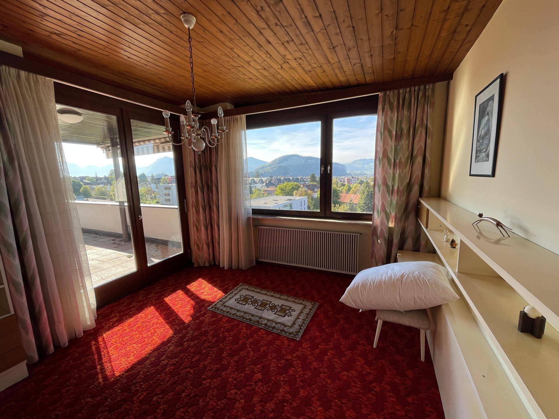 Schlafzimmer mit rotem Teppichboden, Holzdecke und Zugang zu einer Terrasse mit schöner Aussicht.
