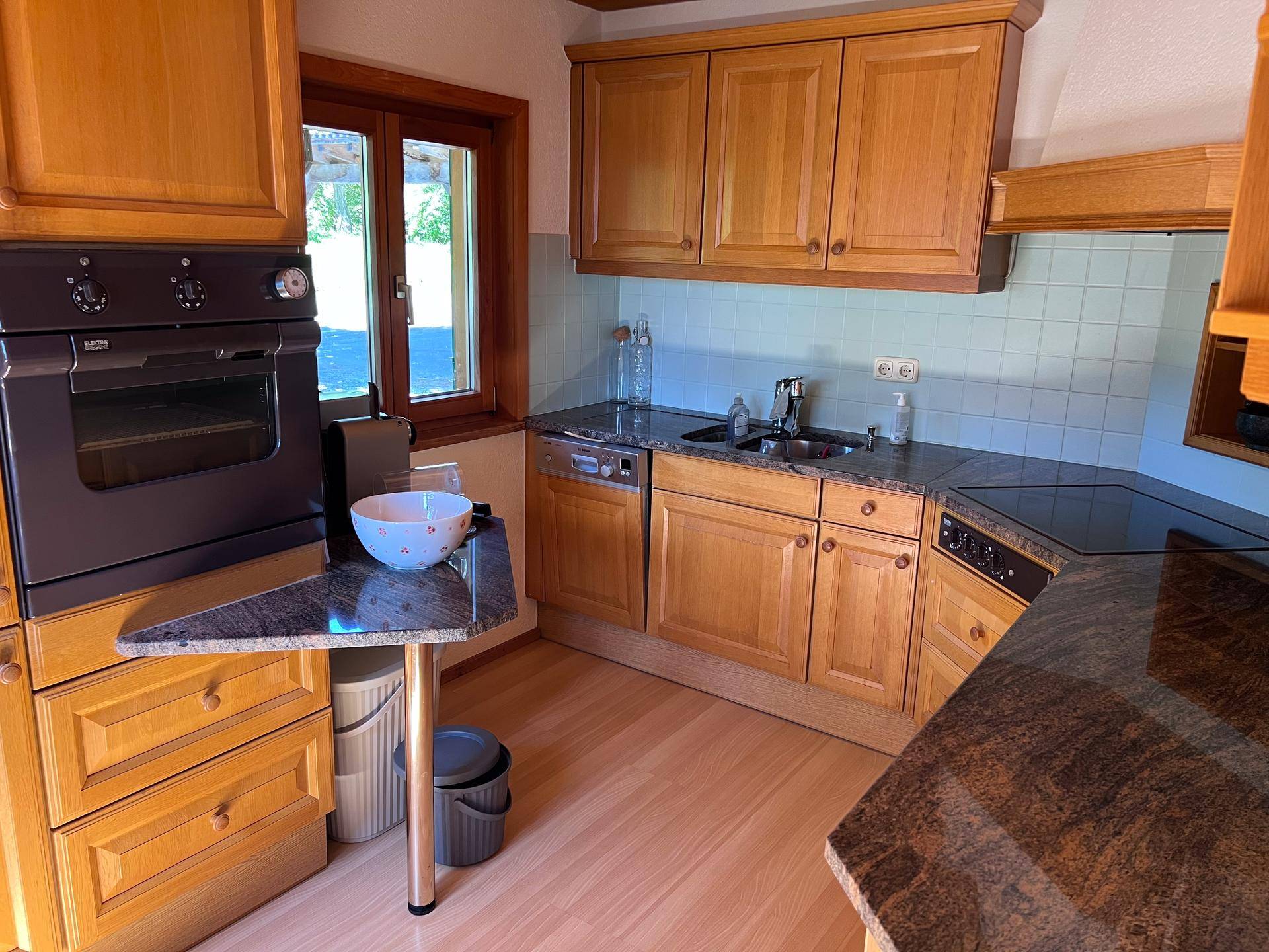 Funktionale Küche mit Holzschränken, Granitarbeitsplatten und integrierten Geräten.