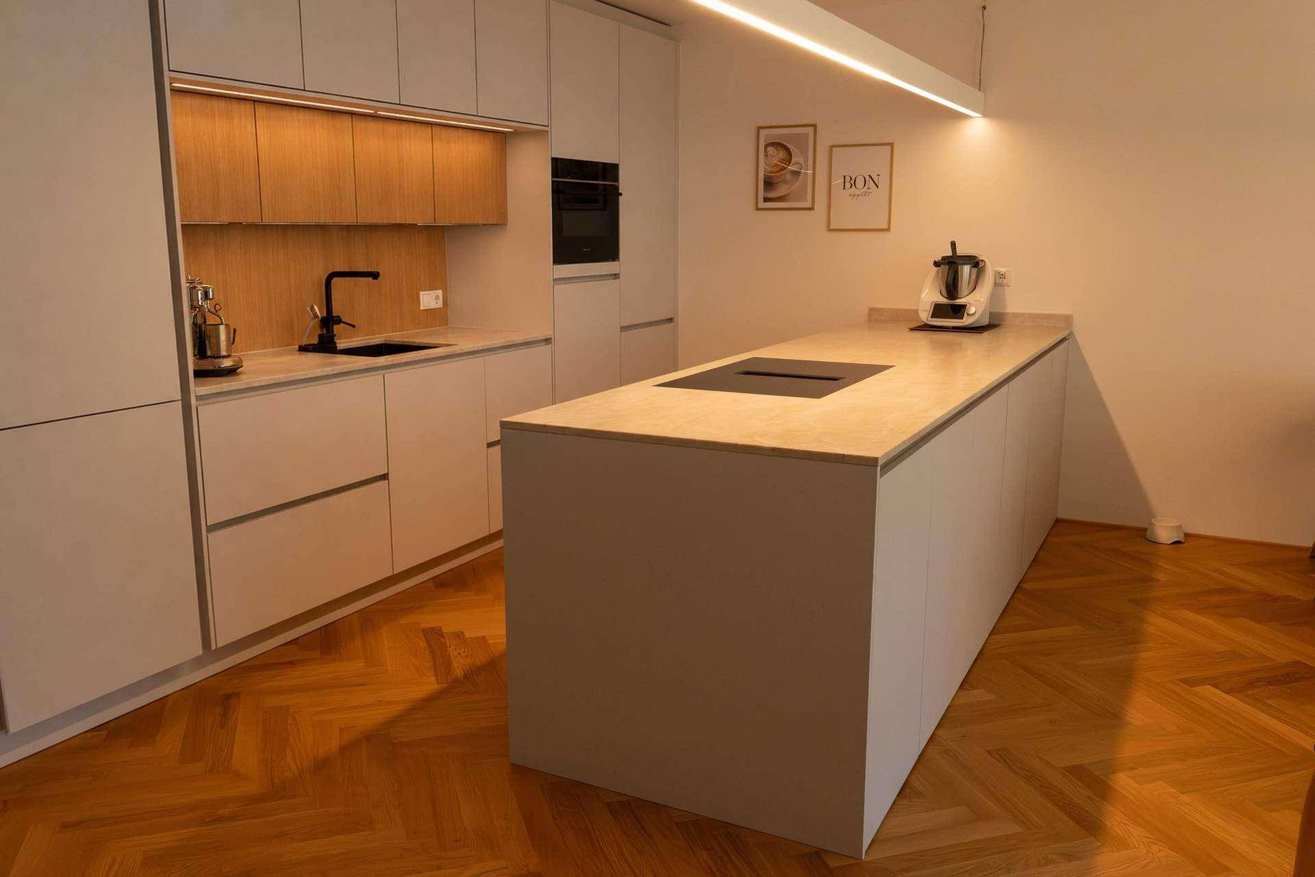Moderne Küche mit Kochinsel, hellen Fronten und integrierten Geräten.