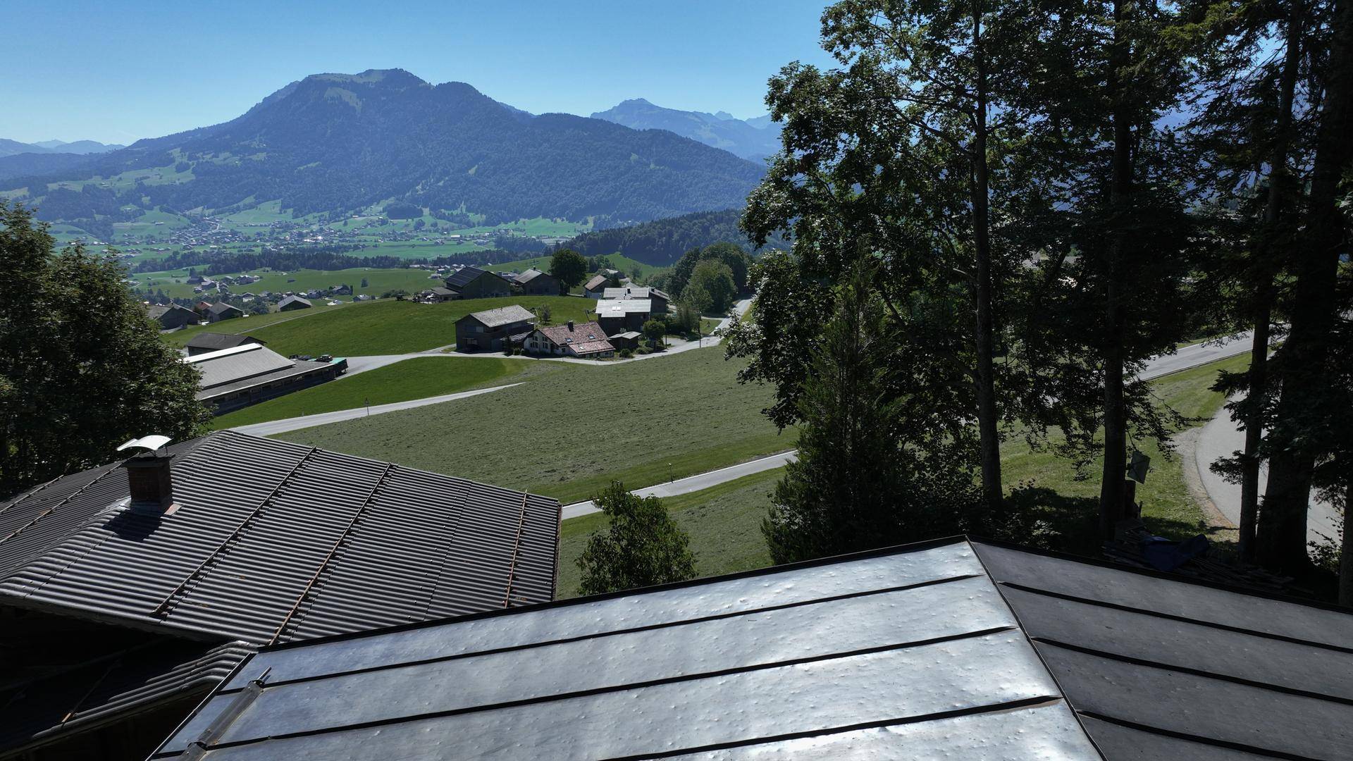 Panoramablick über die Dächer der Häuser auf ein weites Tal und die majestätischen Berge.