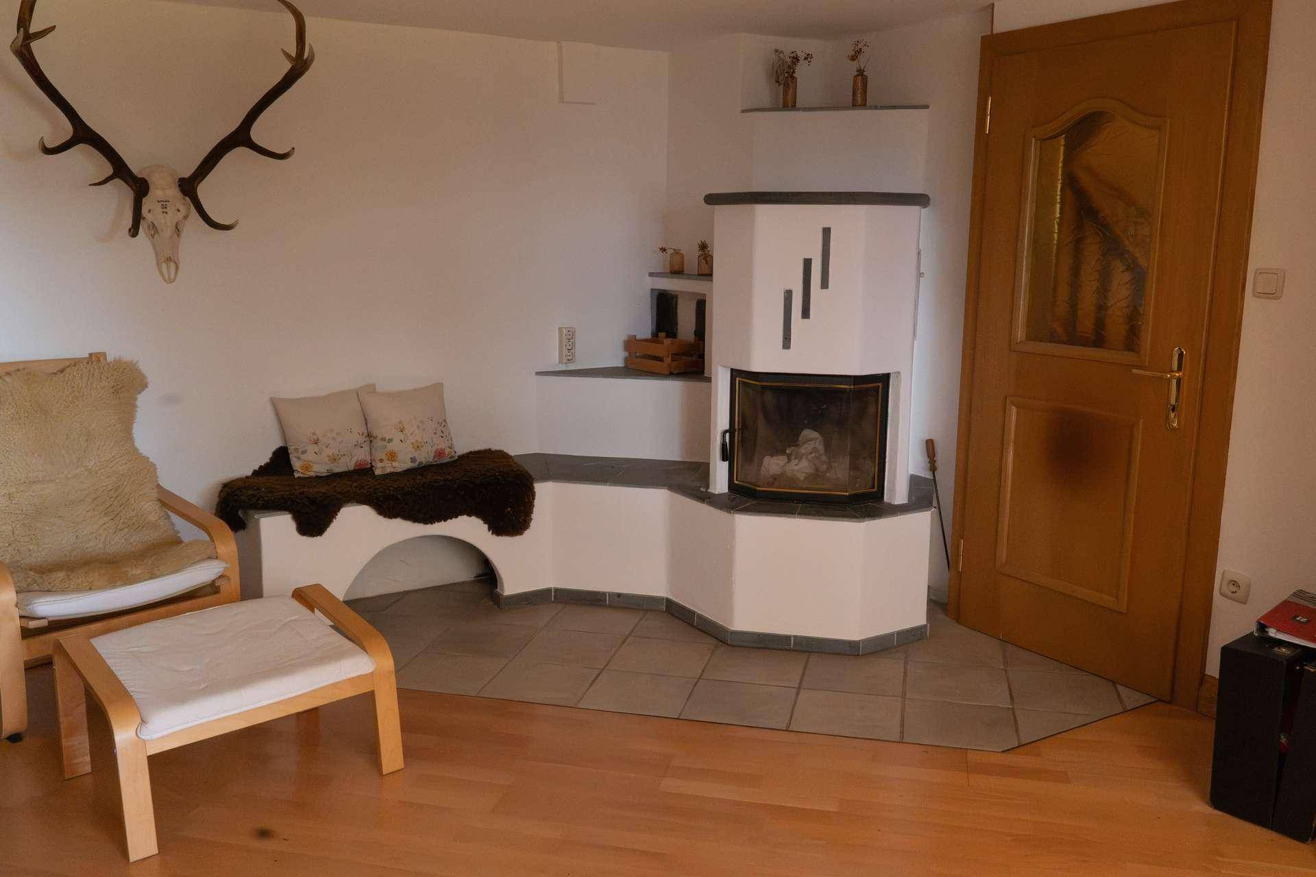 Wohnzimmer mit Kamin, gemütlicher Sitzecke und traditioneller Hirschgeweih-Dekoration.