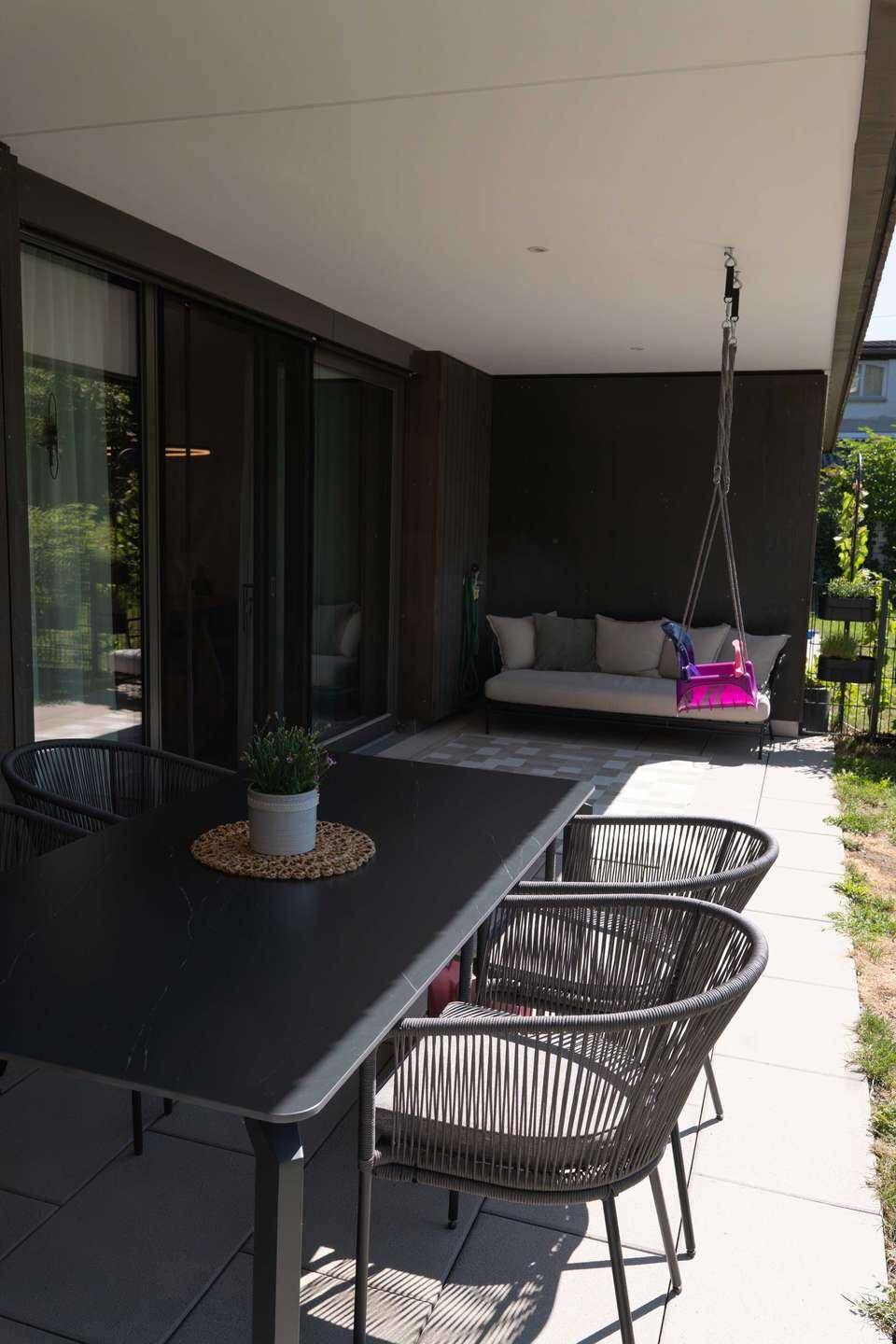 Überdachte Terrasse mit modernen Gartenmöbeln und Zugang zum Wohnbereich.
