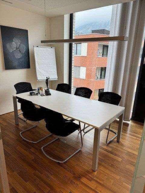 Konferenzraum mit Holzboden, großem Tisch und Blick auf die umliegenden Gebäude, ideal für Besprechungen.