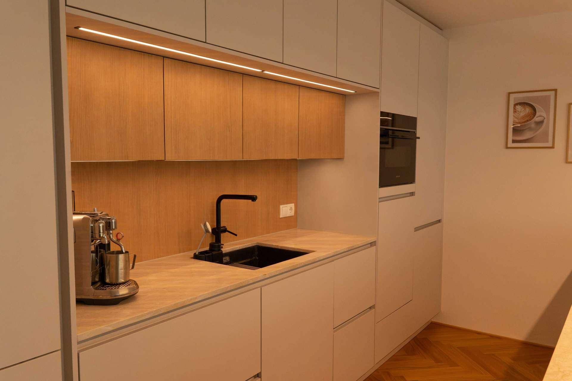 Detailansicht der modernen Küche mit Spülbecken, Kaffeemaschine und Holzrückwand.
