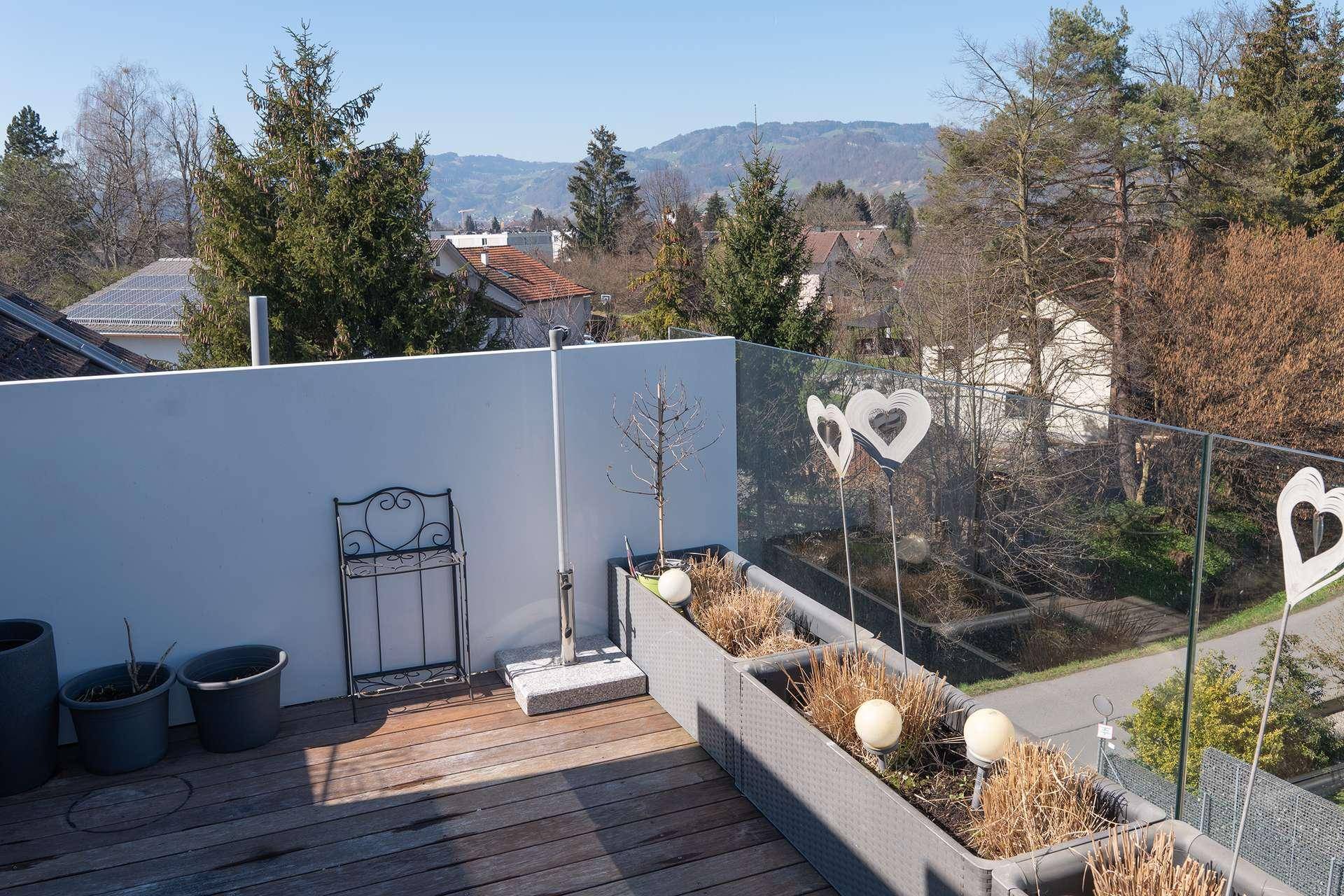 Sonniger Bereich der Dachterrasse mit Glasgeländer und weitem Ausblick.