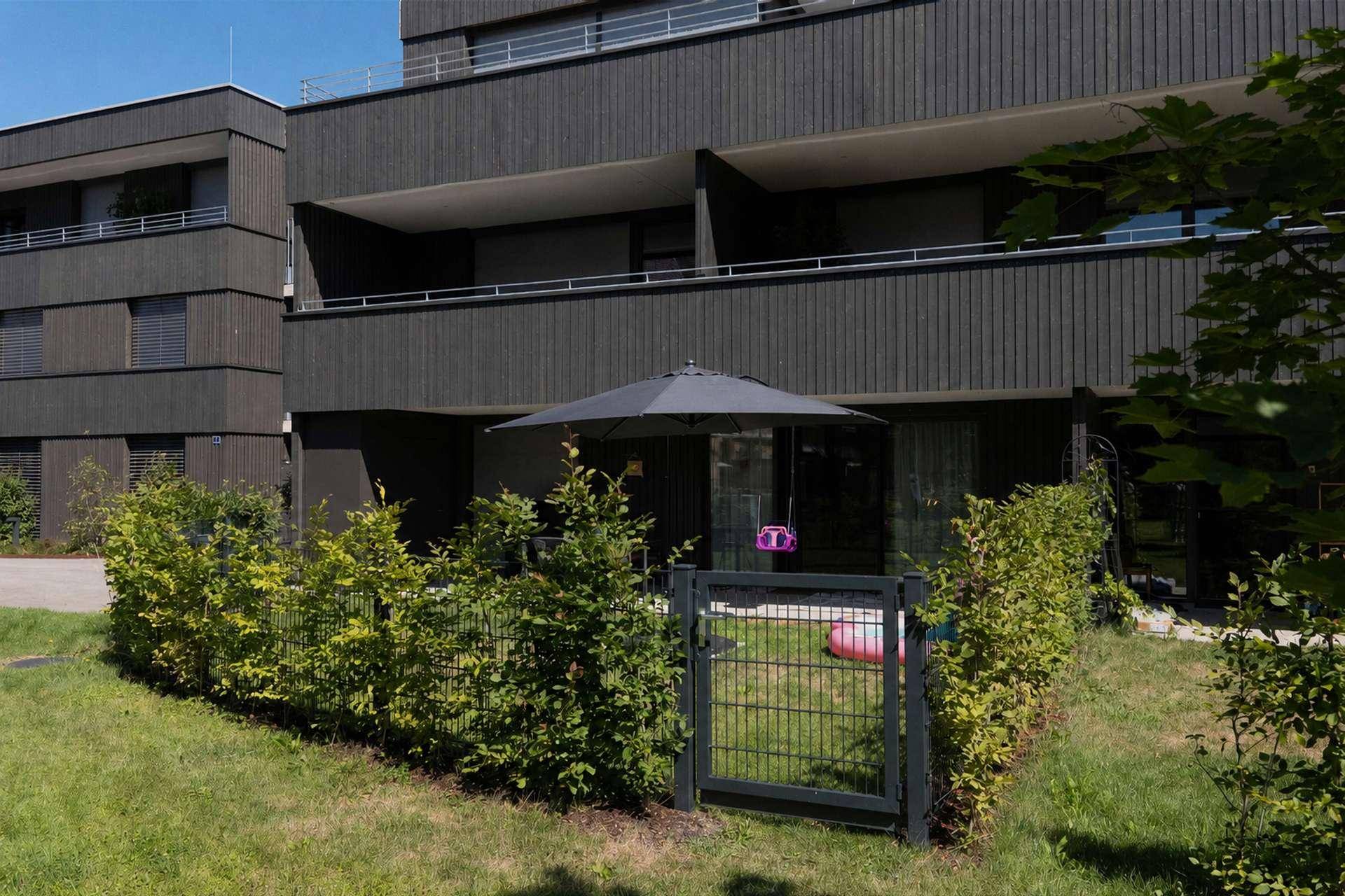 Außenansicht des Gebäudes mit privatem Gartenbereich und Hecke.