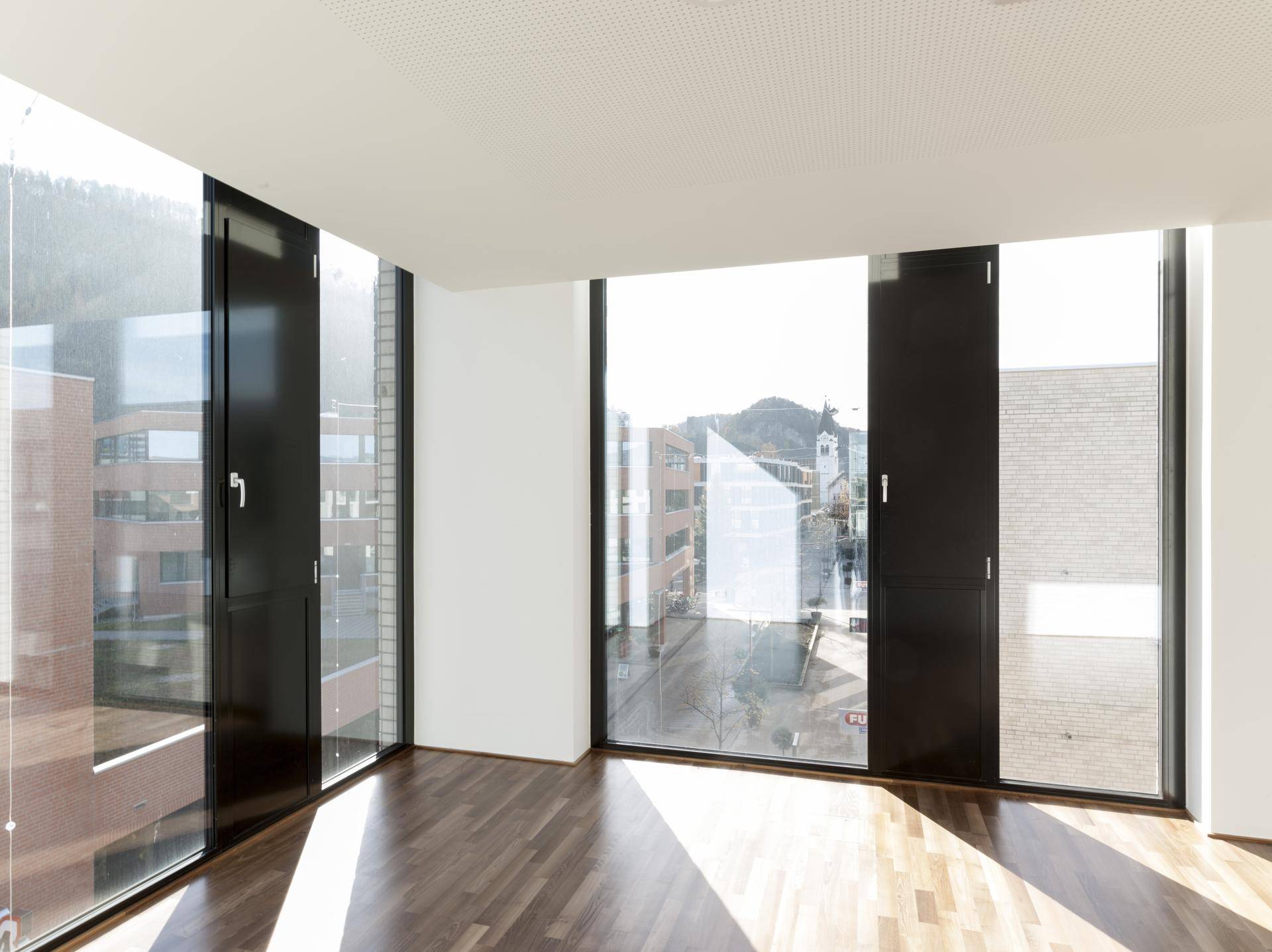 Heller Büroraum mit großen Fenstern und Holzboden, bietet Weitblick auf die Stadt und die umliegende Landschaft.