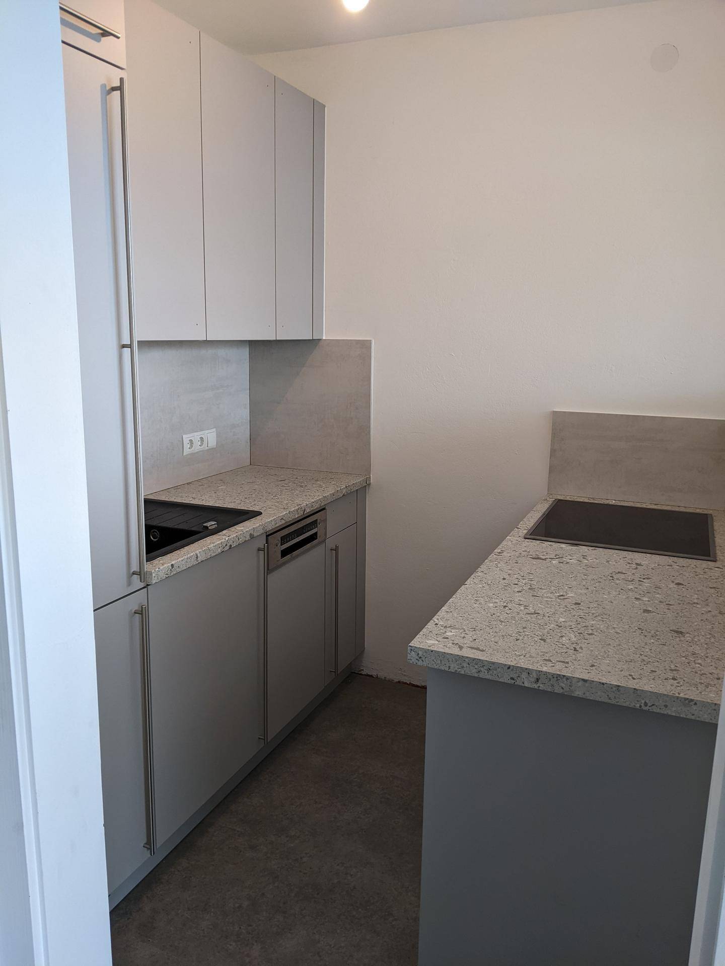 Moderne Küchenzeile mit grauen Schränken, Granitarbeitsplatten und integrierten Geräten.