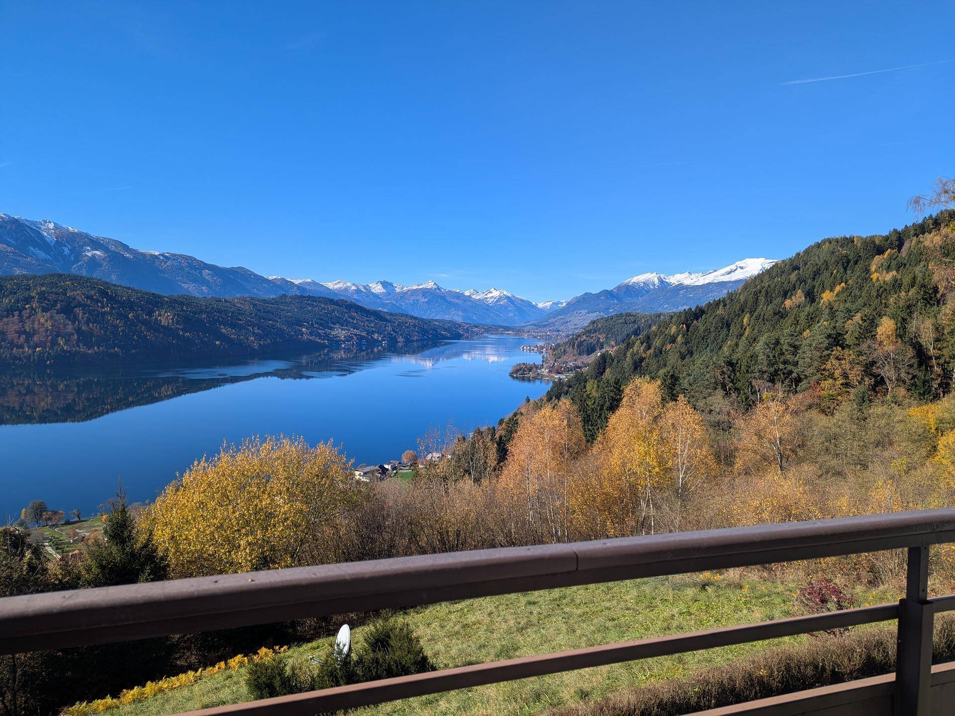 Spektakulärer Panoramablick auf den See und die schneebedeckten Berge unter strahlend blauem Himmel.