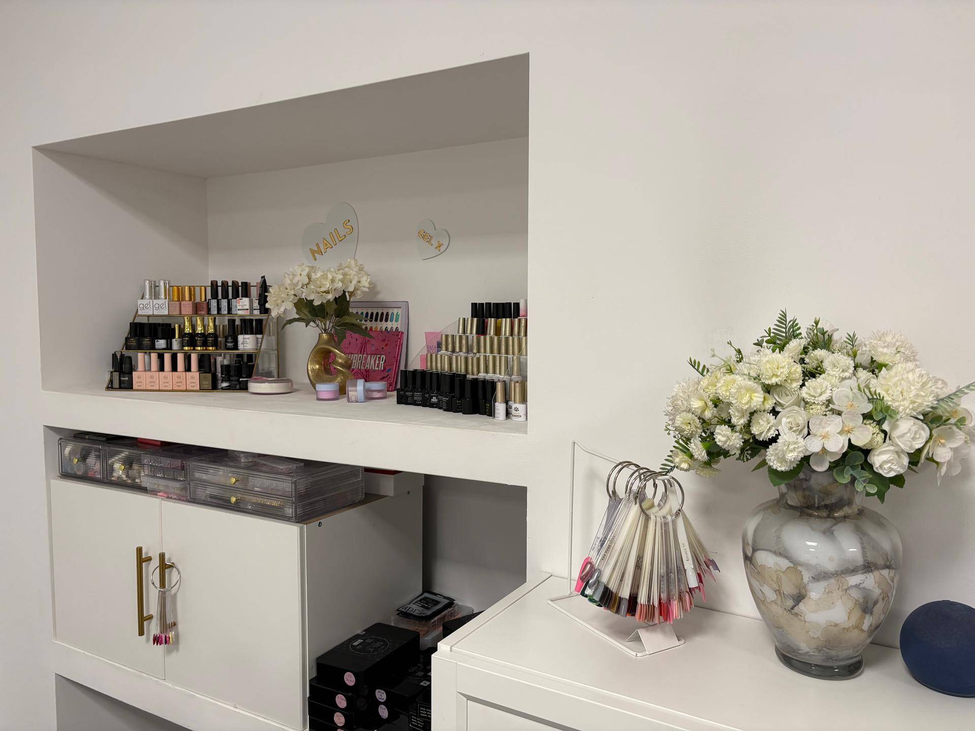 Organisierte Produktpräsentation in Wandnischen und Schränken mit Blumenarrangement.