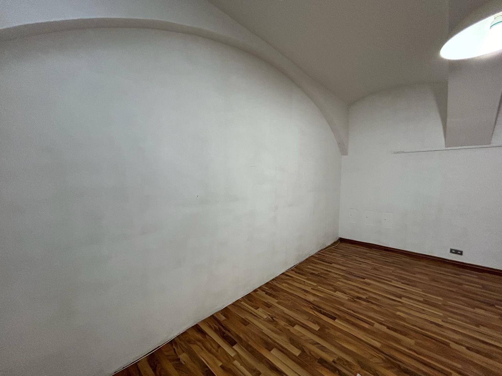 Leerer Raum mit weiß gestrichenen Wänden und Holzboden, der auf neue Einrichtung wartet.