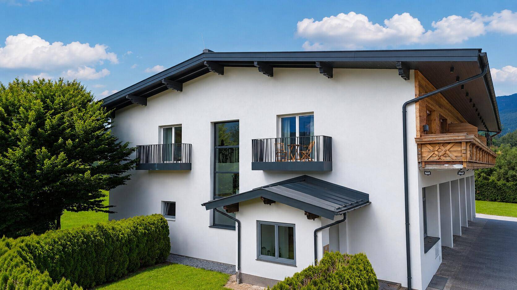 Moderne weiße Fassade eines Hauses mit französischen Balkonen und einem traditionellen Holzbalkon.