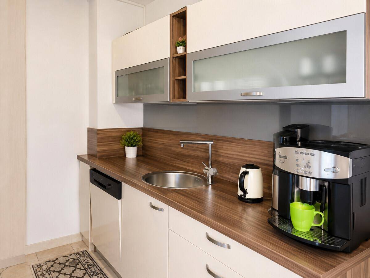 Kleine, moderne Küchenzeile mit Holzarbeitsplatte, Spüle und Kaffeemaschine.
