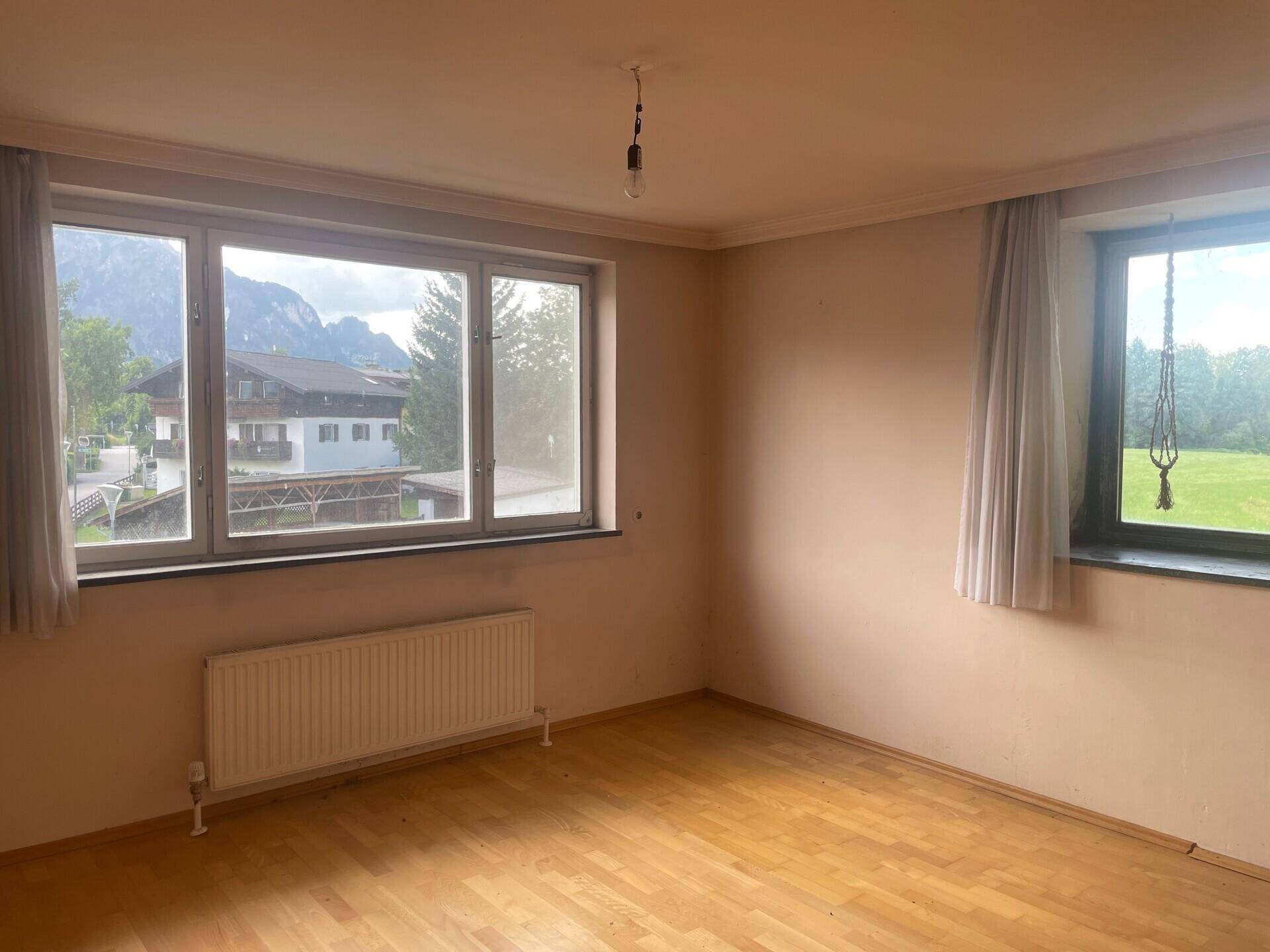 Geräumiges Zimmer mit Holzfußboden, großen Fenstern und Bergblick.
