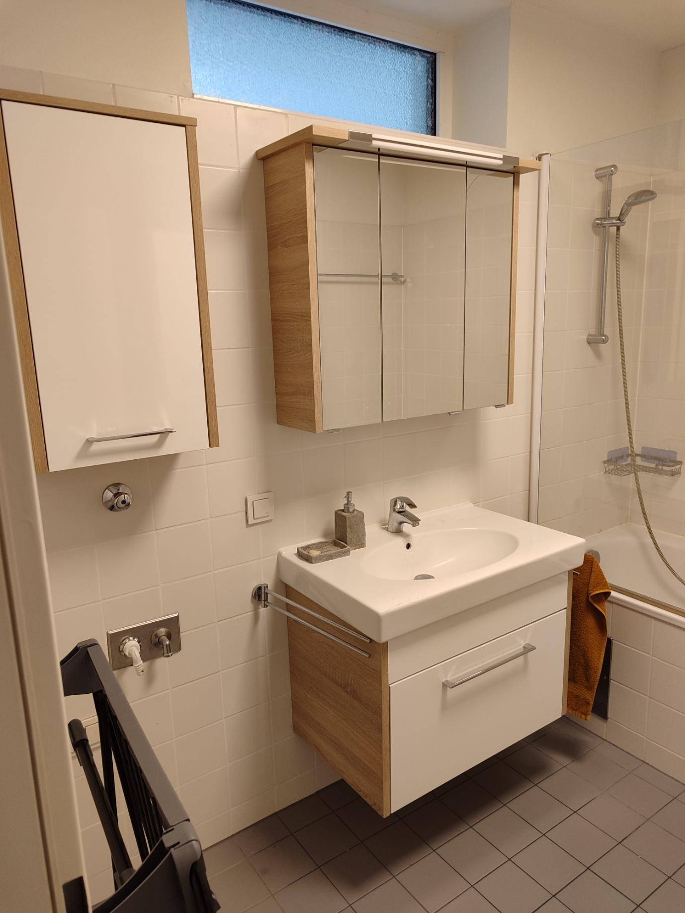 Modernes Badezimmer mit Waschtisch, Spiegelschrank und Duschmöglichkeit.