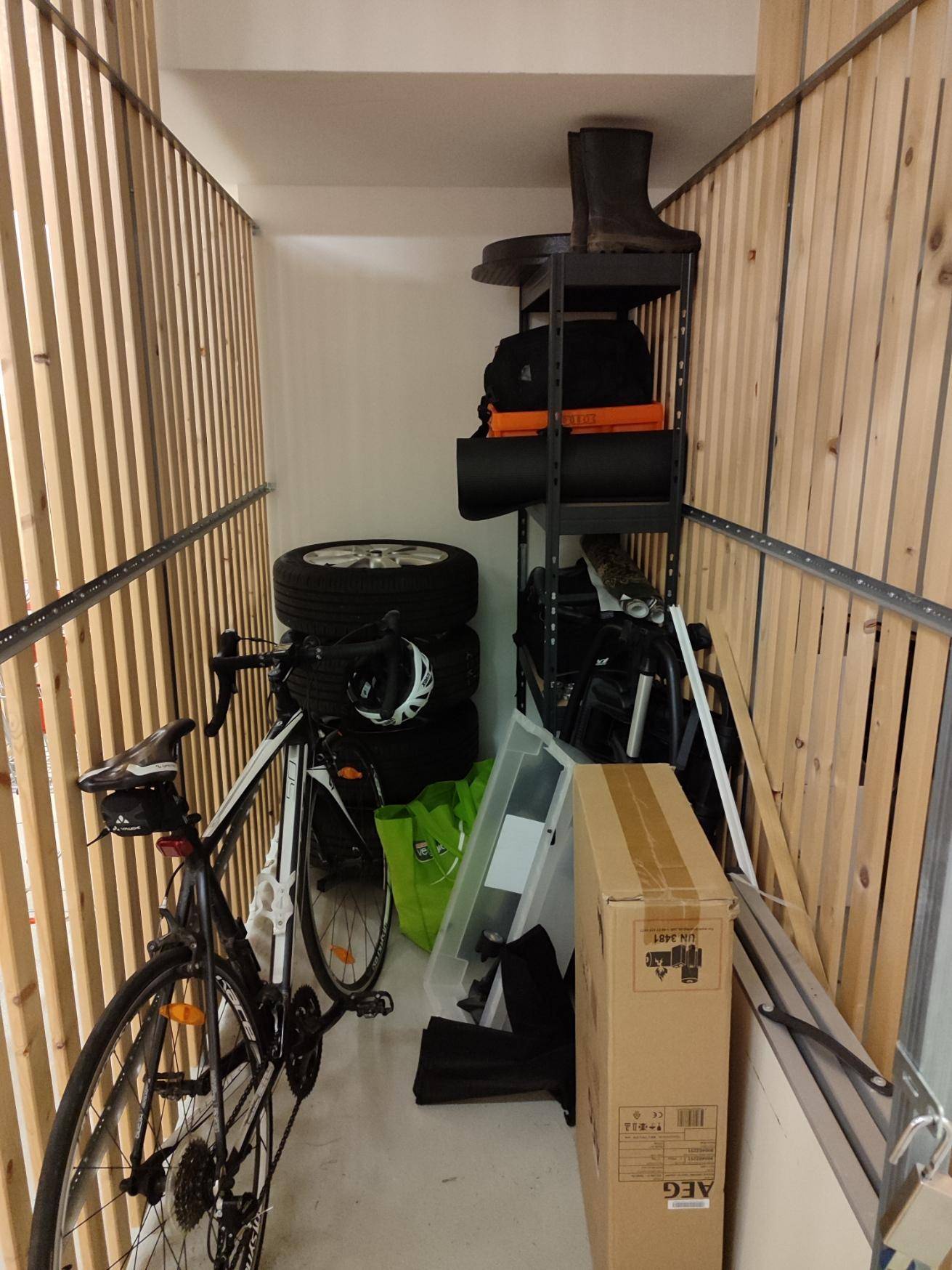 Praktischer Abstellraum mit Holzlattenwänden, Regalen und Stauraum für Fahrräder.