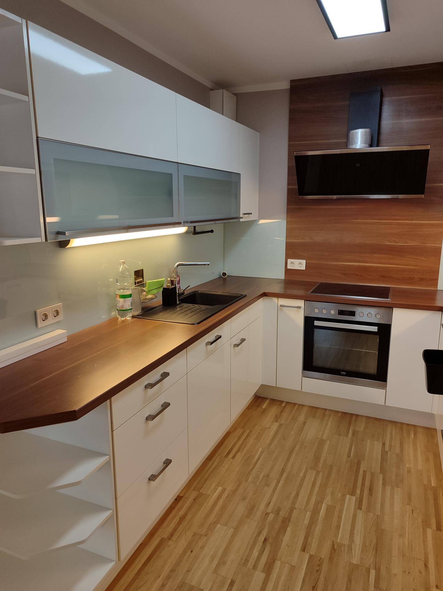 Moderne Küche mit weißen Schränken, Holz-Arbeitsplatten und integrierten Geräten.