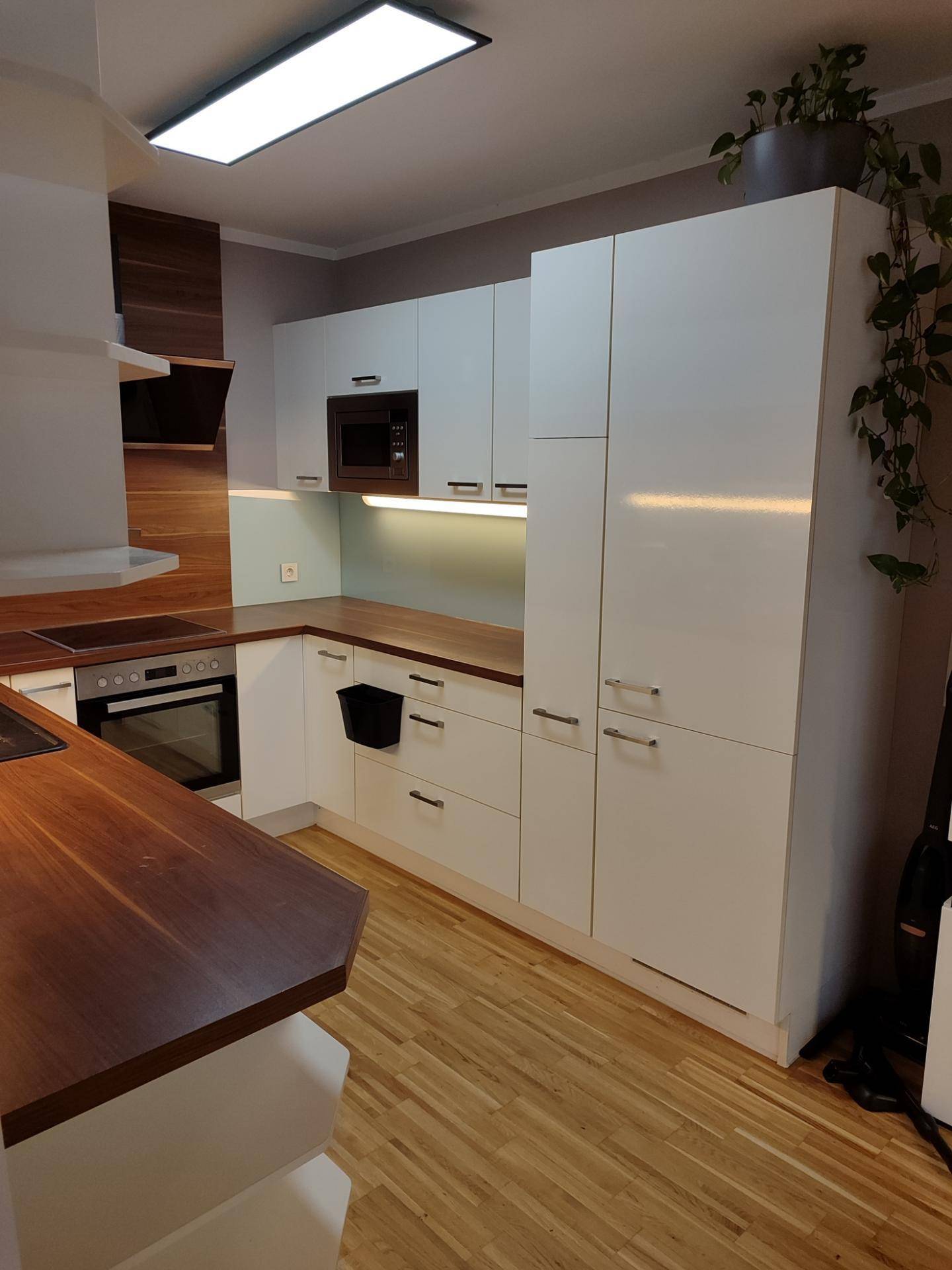 Voll ausgestattete moderne Küche mit weißen Schränken und Holz-Arbeitsplatten.