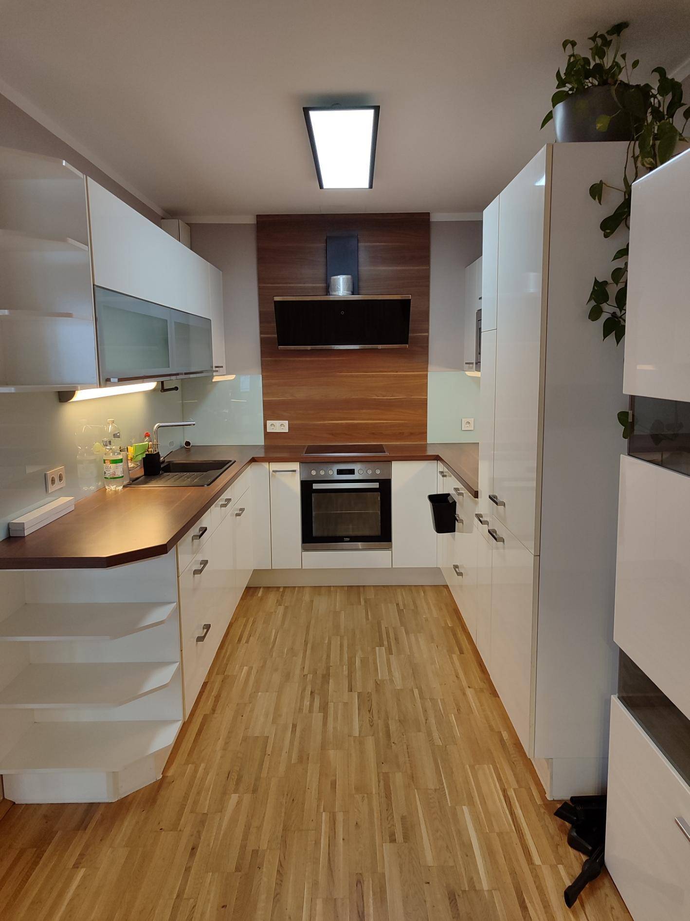 Geräumige, voll ausgestattete moderne Küche mit weißen Schränken und Parkettboden.