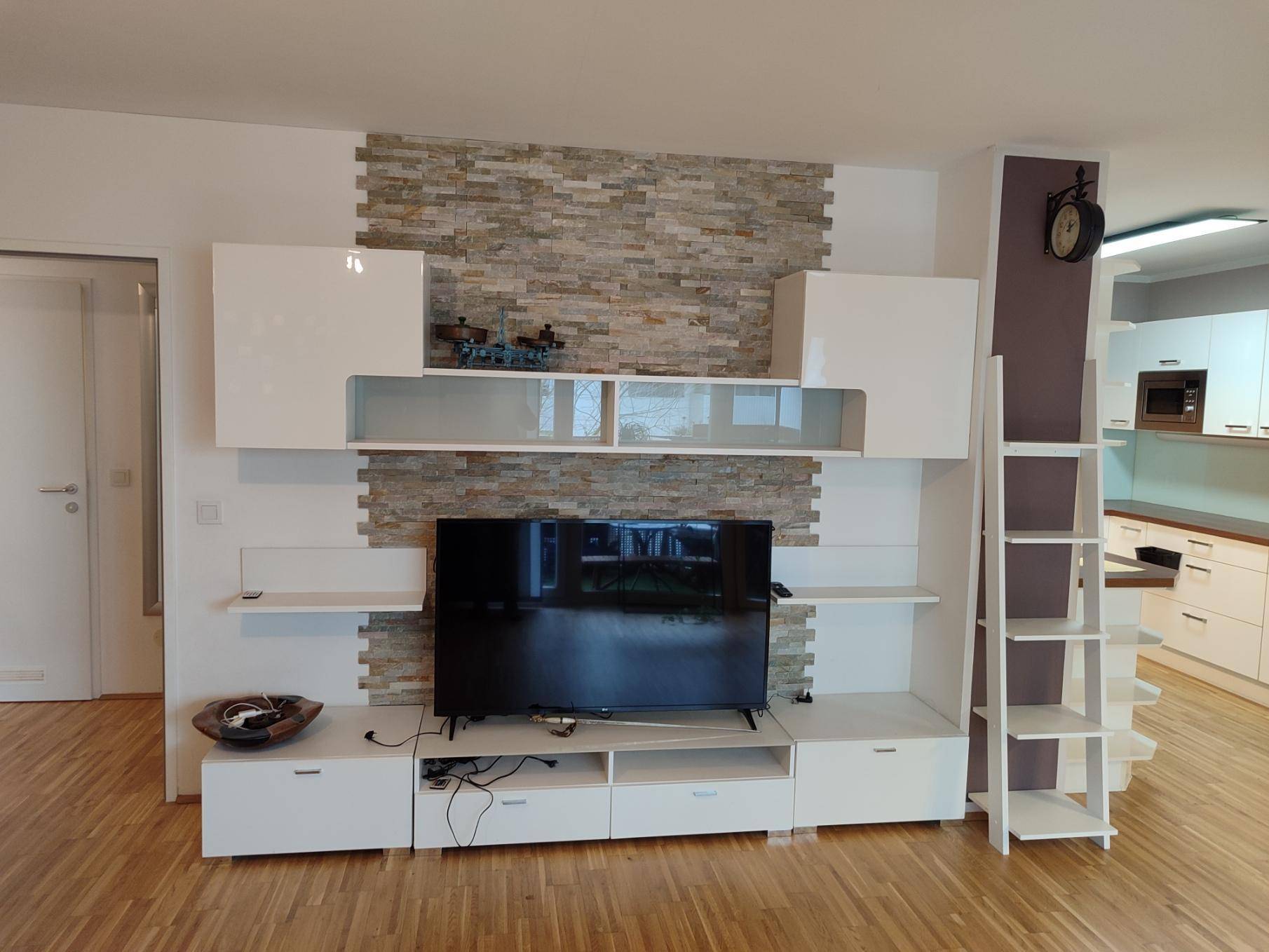 Modernes Wohnzimmer mit weißer Medienwand und dekorativer Steinwand.