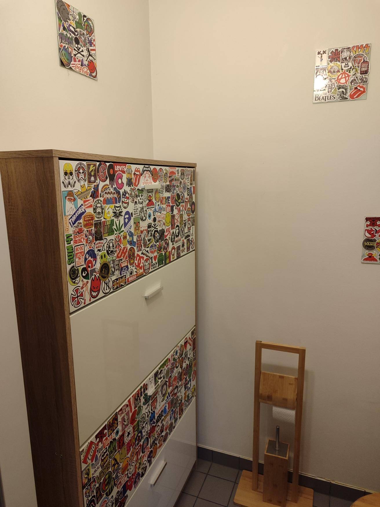 Schrank mit bunten Aufklebern im Gäste-WC, bietet zusätzlichen Stauraum.