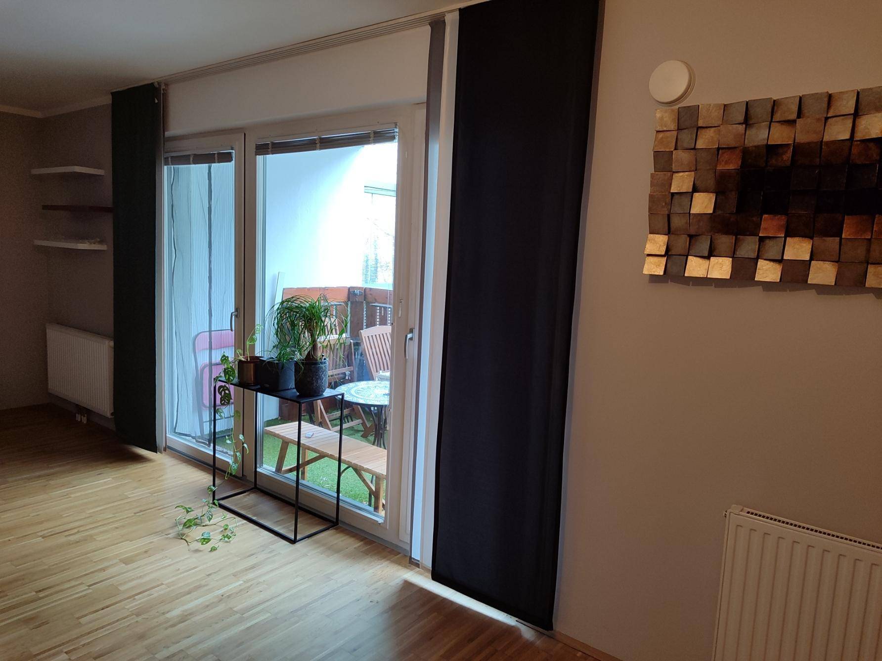 Helles Wohnzimmer mit Zugang zum Balkon und Parkettboden.