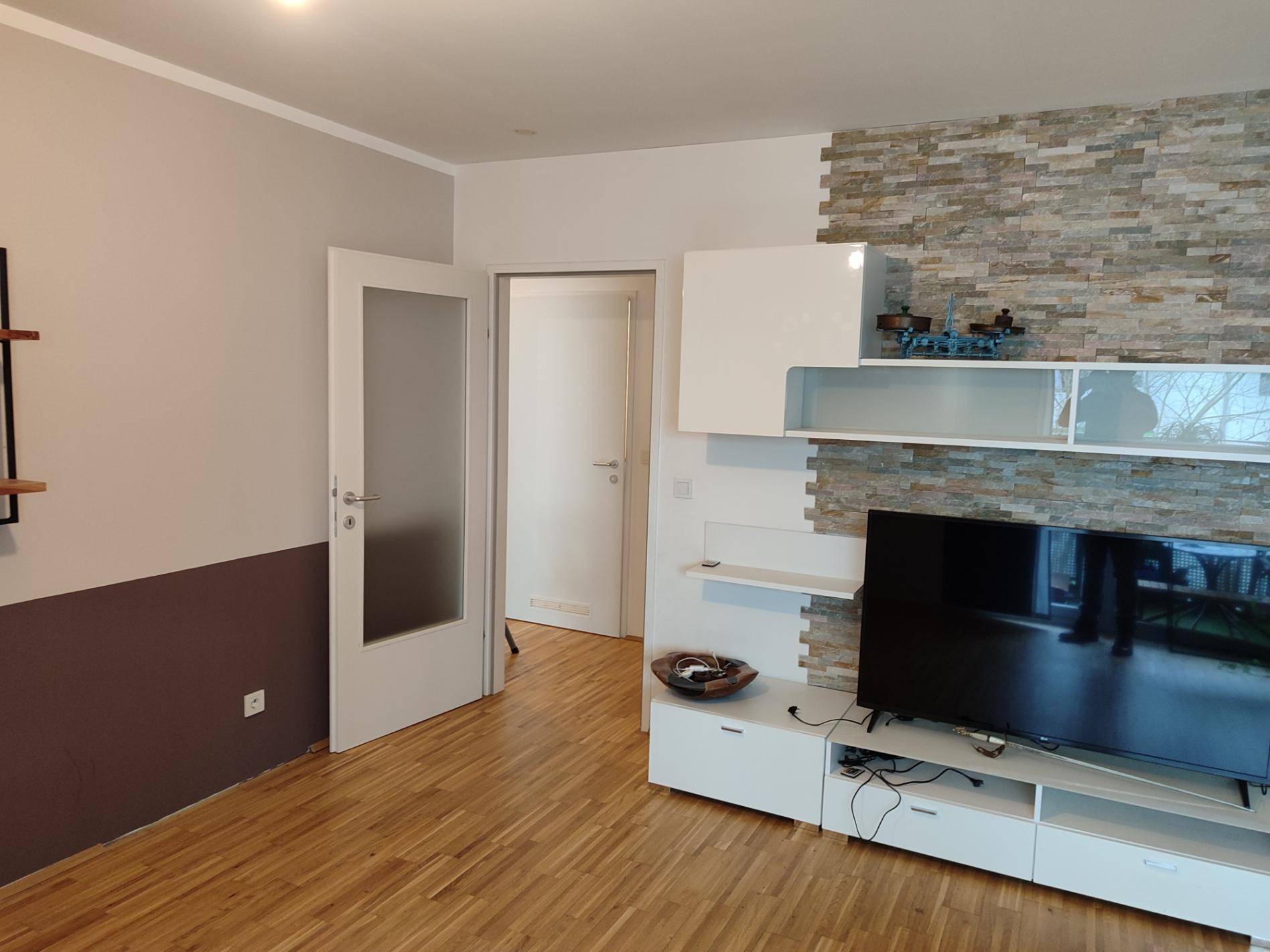 Wohnzimmereingang mit moderner Medienwand und Steinakzenten.