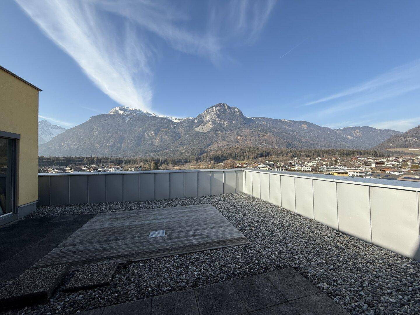 Große Dachterrasse mit Kies und Holzdeck, bietet einen weiten Blick auf die umliegende Berglandschaft.