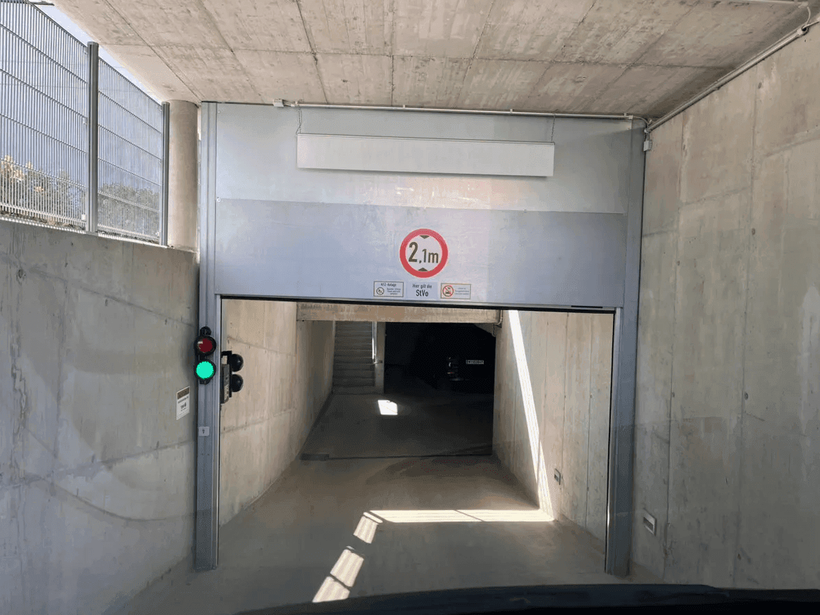 Einfahrt zur Tiefgarage mit Höhenbegrenzung von 2,1 Metern und einer Ampel zur Verkehrsregelung.