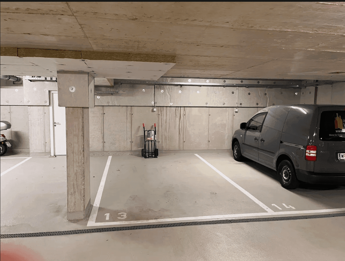 Tiefgarage mit Betonwänden und -decken, markierten Stellplätzen und einem geparkten Lieferwagen.
