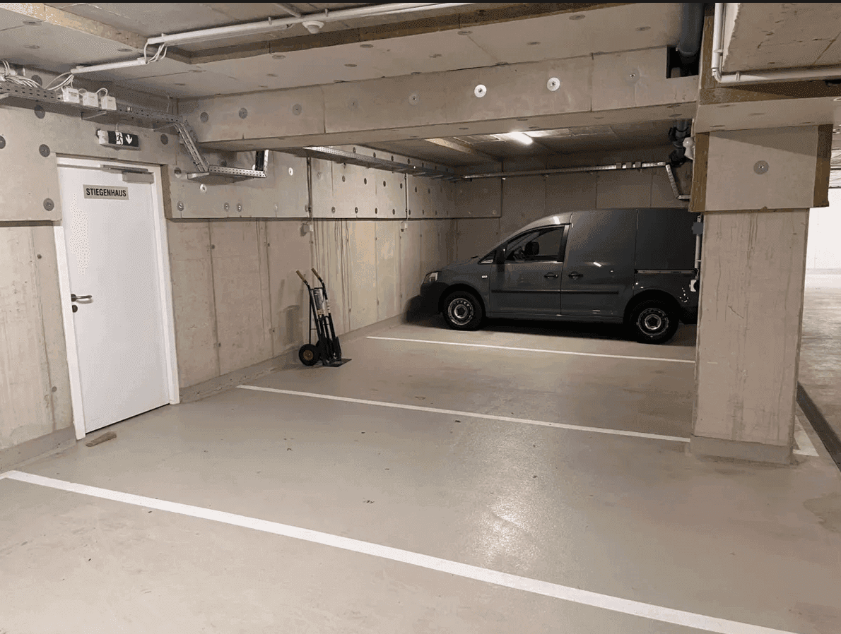 Tiefgarage mit Betonstruktur, einem Lieferwagen und einer Tür zum Treppenhaus, die den Zugang erleichtert.