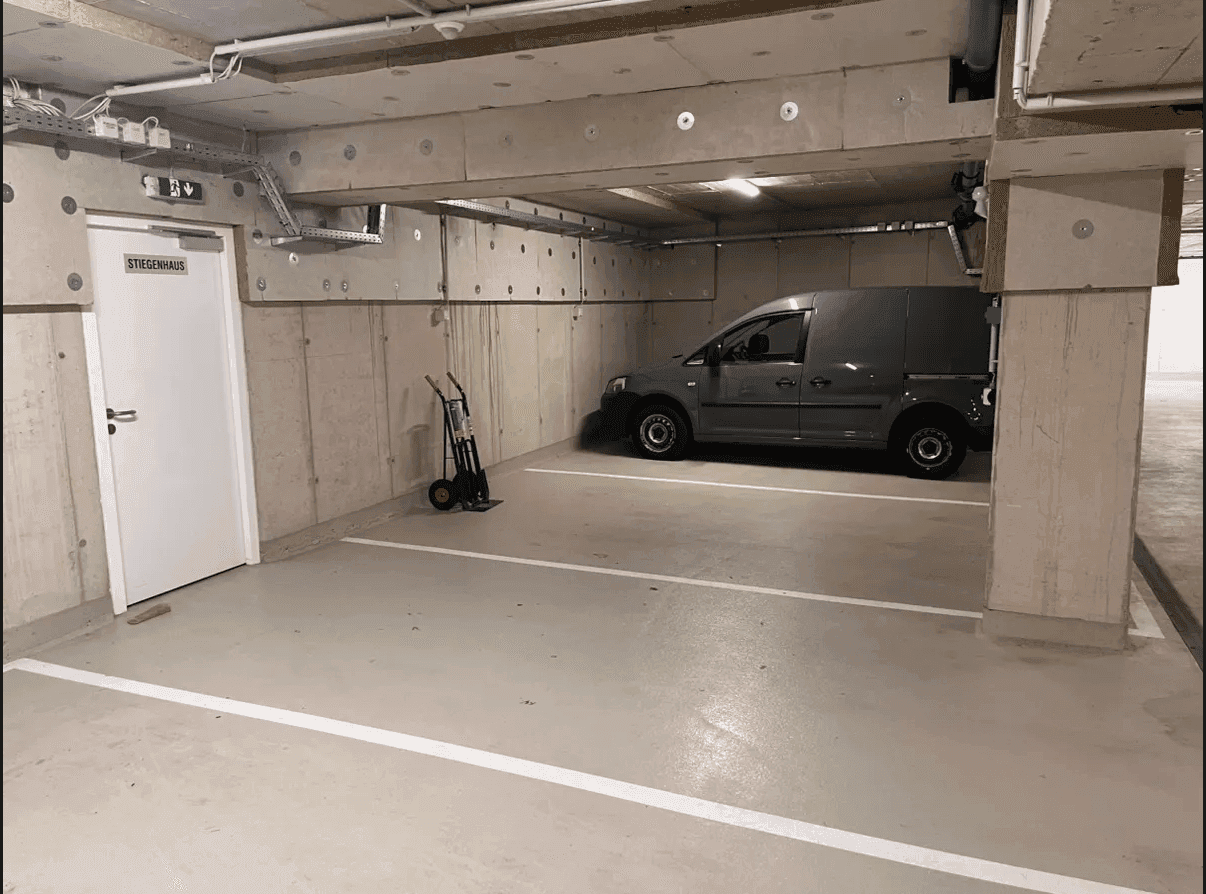 Tiefgarage mit Betonstruktur, einem Lieferwagen und einer Tür zum Treppenhaus, die den Zugang erleichtert.