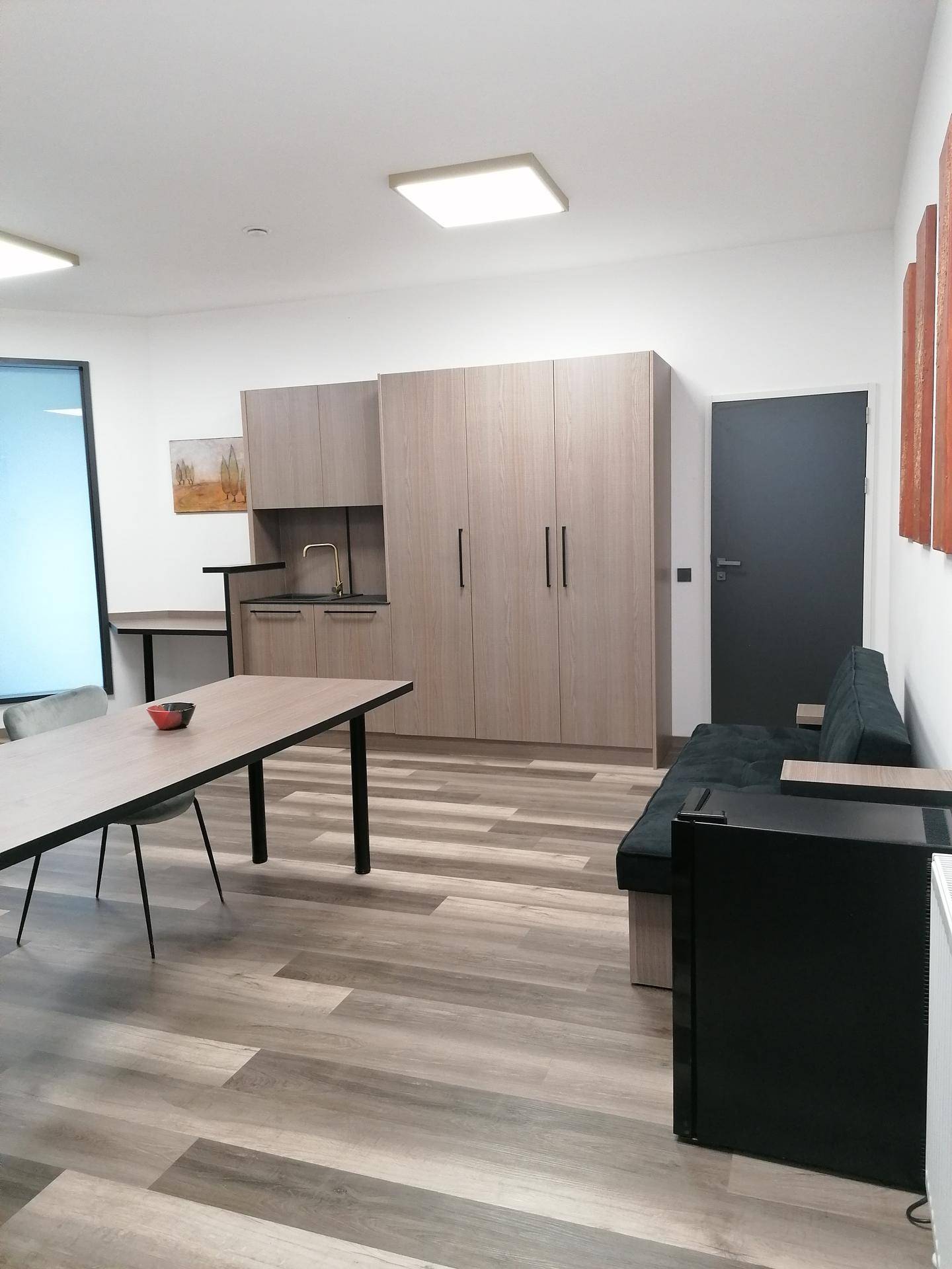 Geräumiger Mehrzweckraum mit Küchenzeile, Sofa und modernem Esstisch.