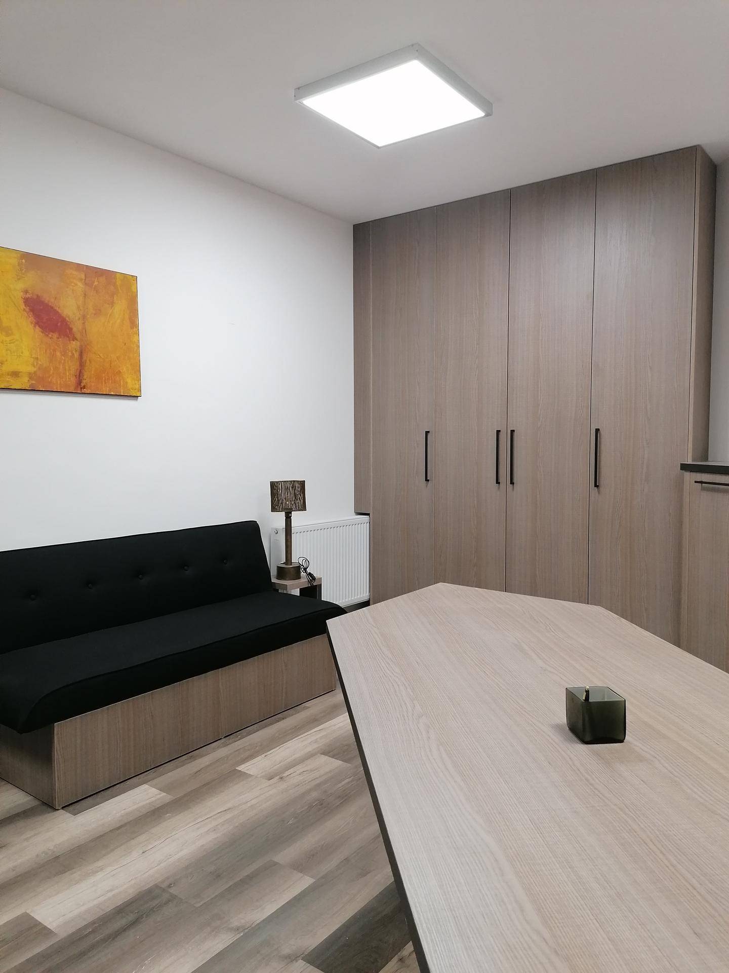 Gemütlicher Bereich im Mehrzweckraum mit Sofa, Stehlampe und großen Einbauschränken.