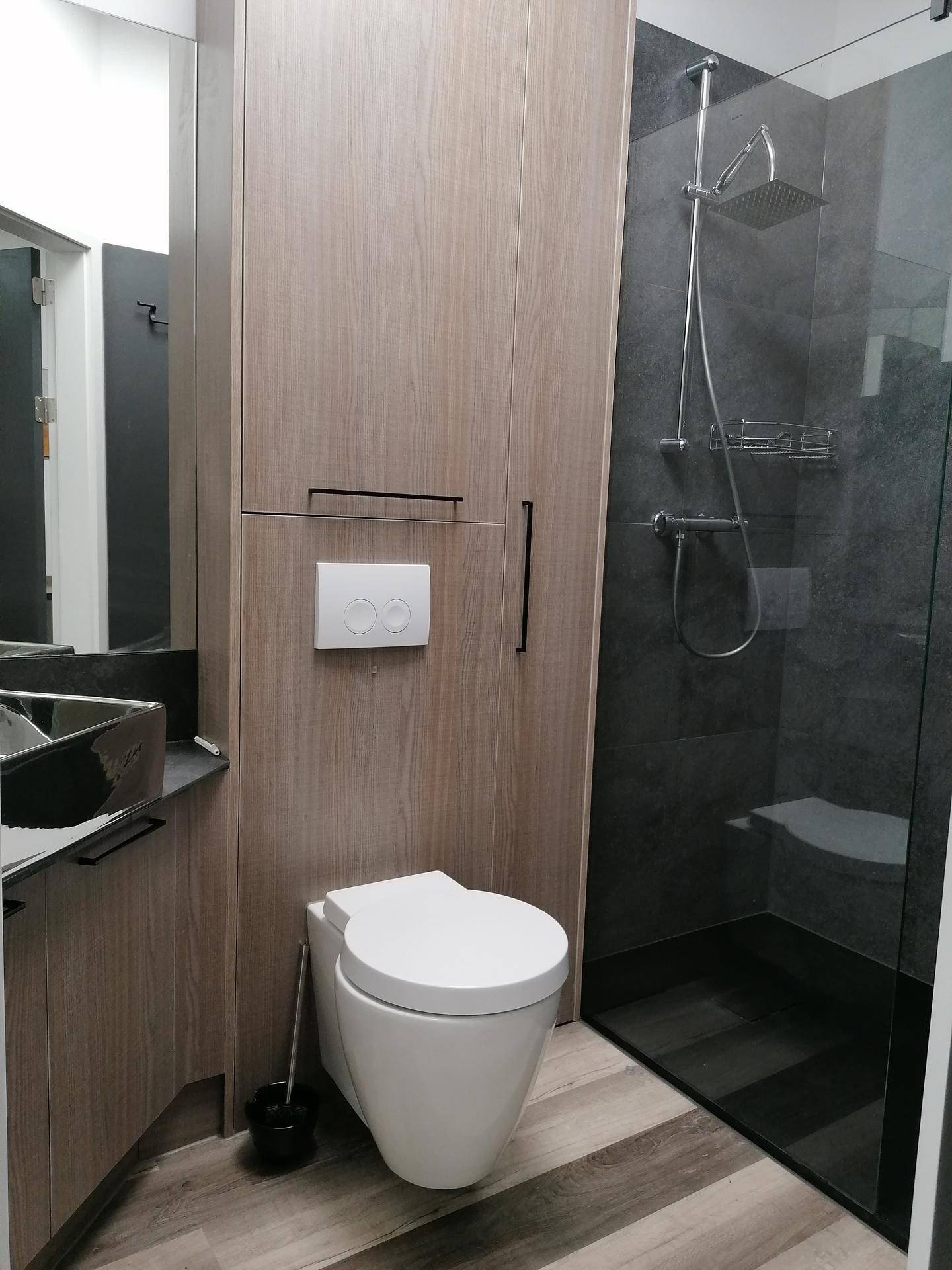 Modernes Badezimmer mit wandhängendem WC, begehbarer Dusche und Holzschränken.