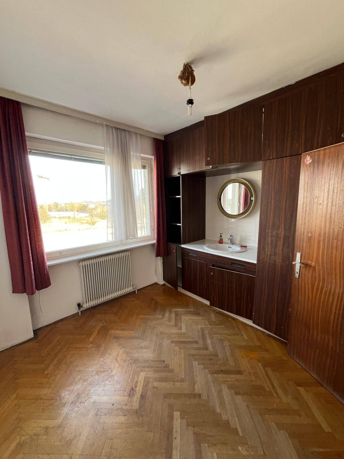 Schlafzimmer mit Parkettboden, Einbauschränken und integriertem Waschbecken.