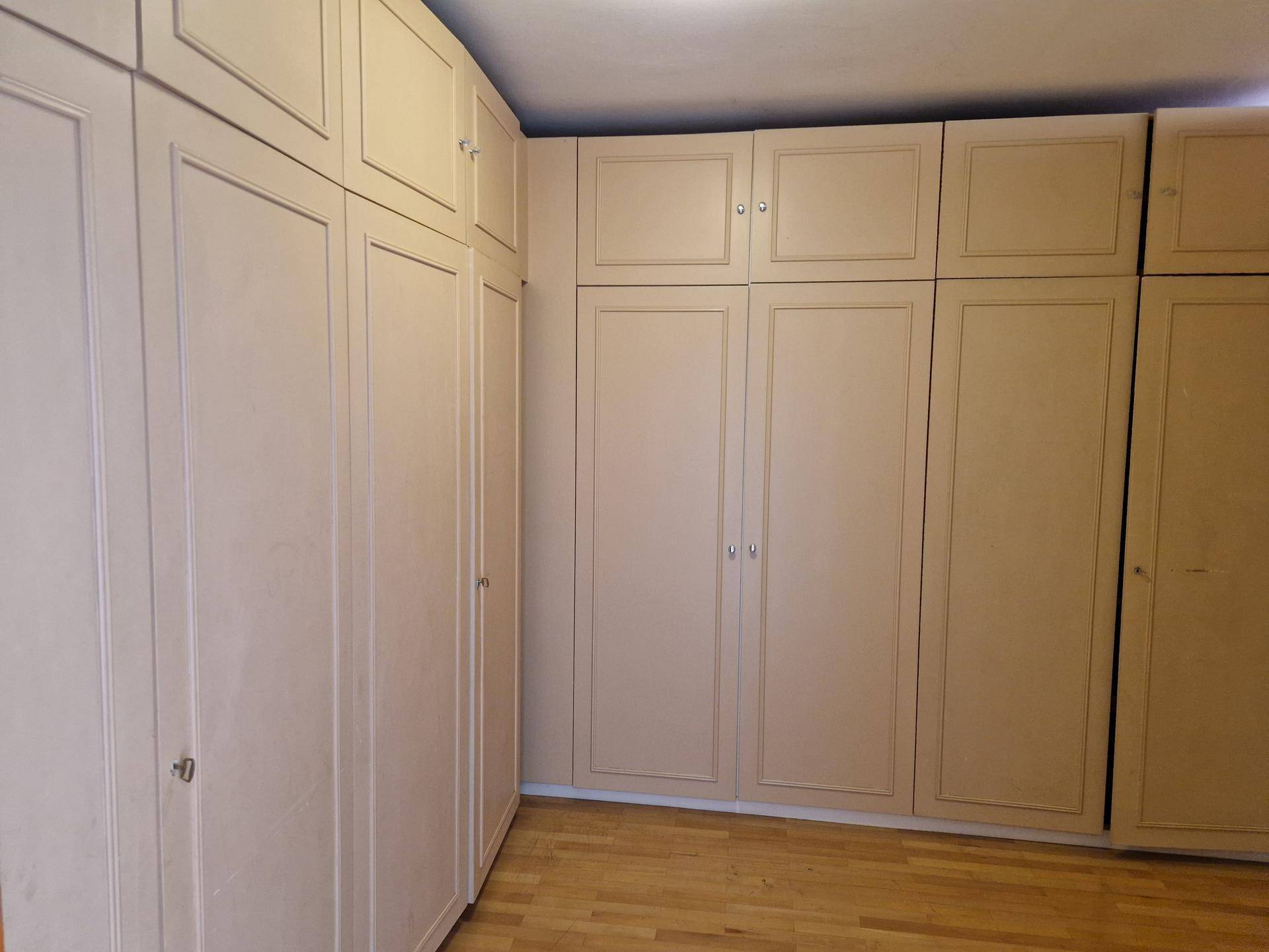 Schlafzimmer mit Einbauschränken in hellem Holzton und Parkettboden.
