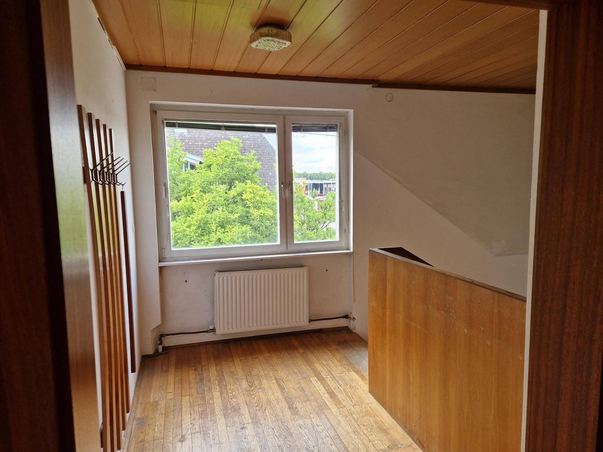 Heller Bereich im Obergeschoss mit Holzdecke, Parkettboden und Fenster.