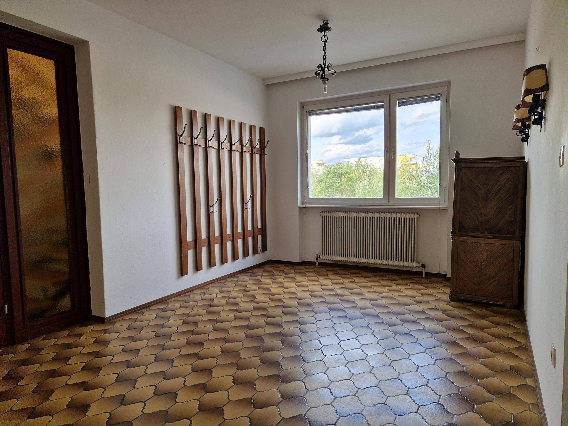 Heller Eingangsbereich mit gemustertem Boden, Garderobe und Fenster mit Ausblick.