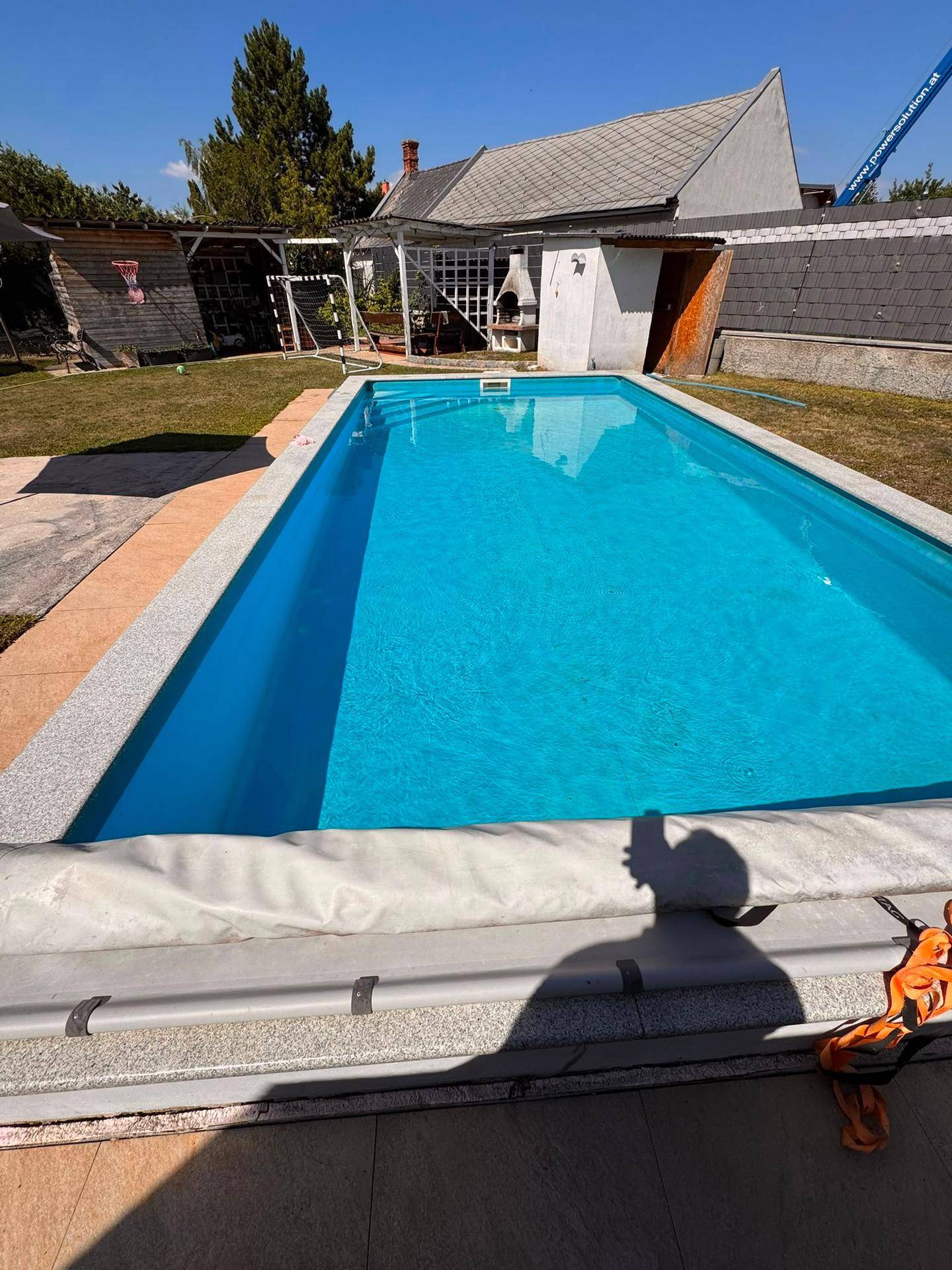 Außenbereich mit großem Swimmingpool, gepflegtem Rasen und Grillplatz im Hintergrund.