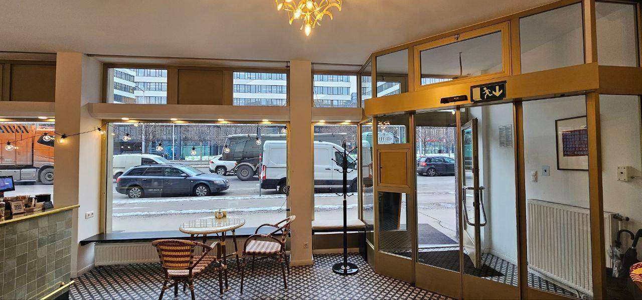 Heller Café-Sitzbereich mit Blick auf die Straße durch große Fenster und gemütlichen Tischen.