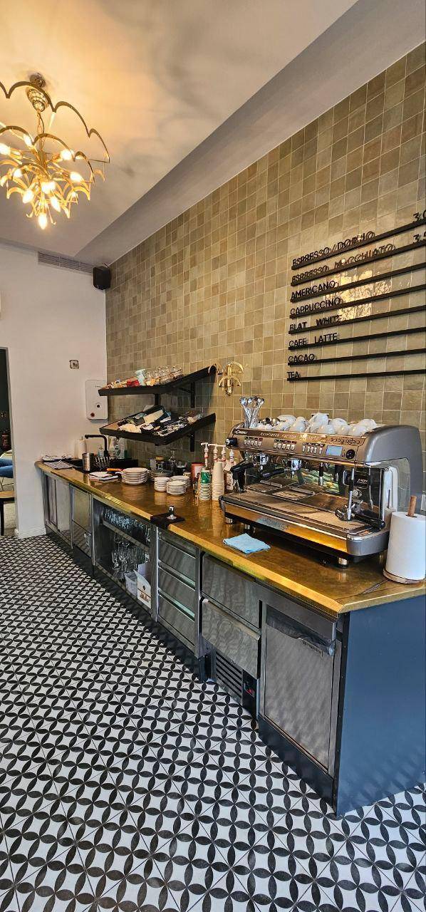 Professionelle Barista-Station mit Espressomaschine, gefliester Wand und gemustertem Boden.