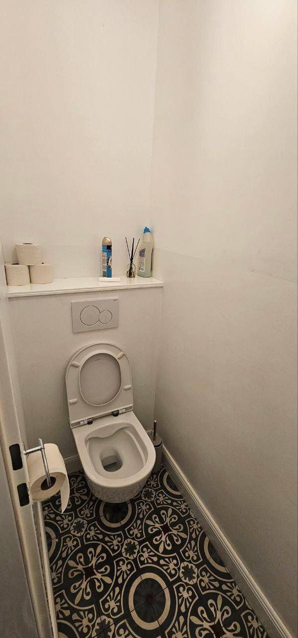 Kleine Toilette mit Wand-WC und auffälligen gemusterten Bodenfliesen in Schwarz-Weiß.