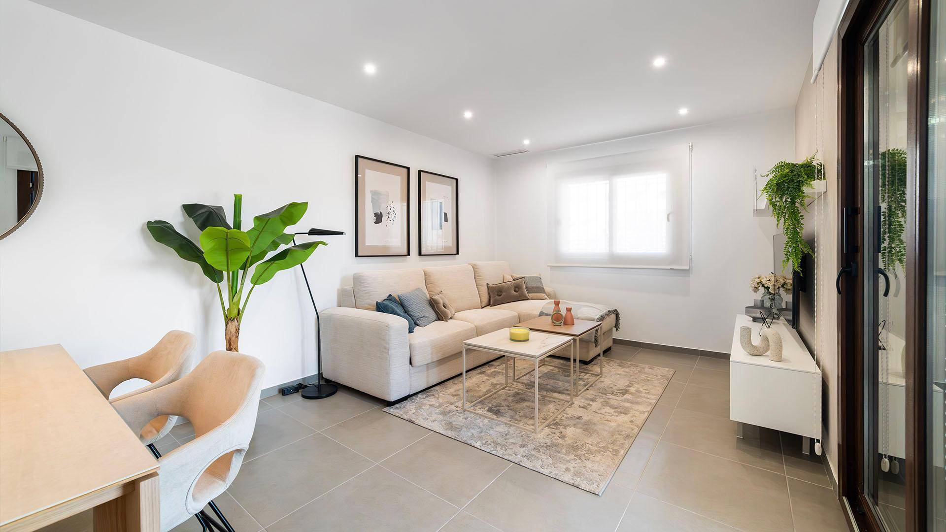 Gemütliches Wohnzimmer mit hellem Sofa, modernen Dekorationen und Zugang zum Außenbereich.