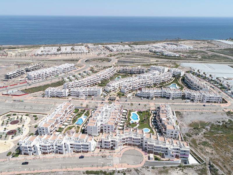 Luftaufnahme einer weitläufigen Wohnanlage am Meer mit zahlreichen Pools und Grünflächen.
