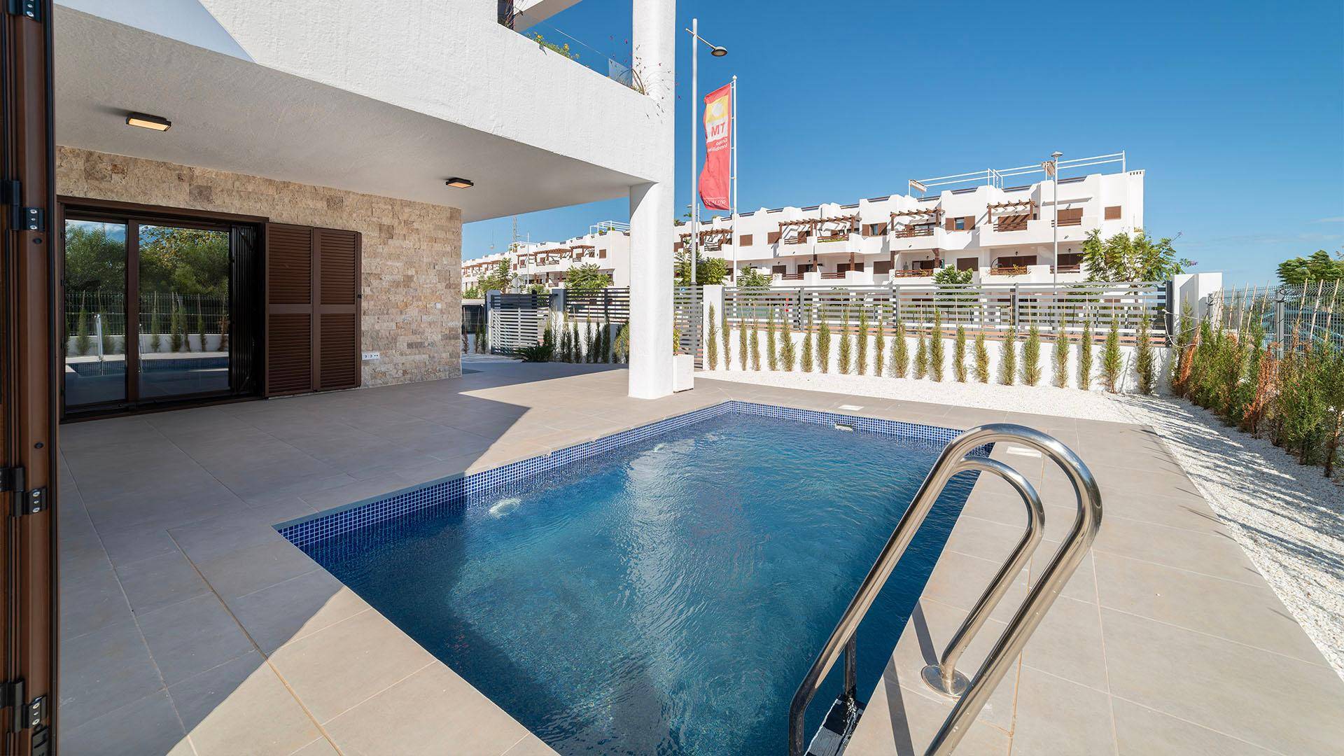 Moderner Außenbereich mit privatem Pool und gefliester Terrasse, umgeben von Grünflächen.
