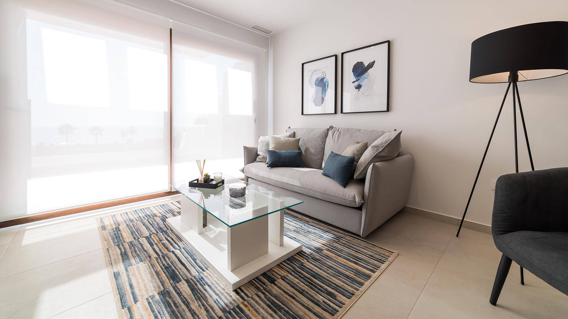 Gemütliches Wohnzimmer mit beigem Sofa, modernem Teppich und großen Fenstern.