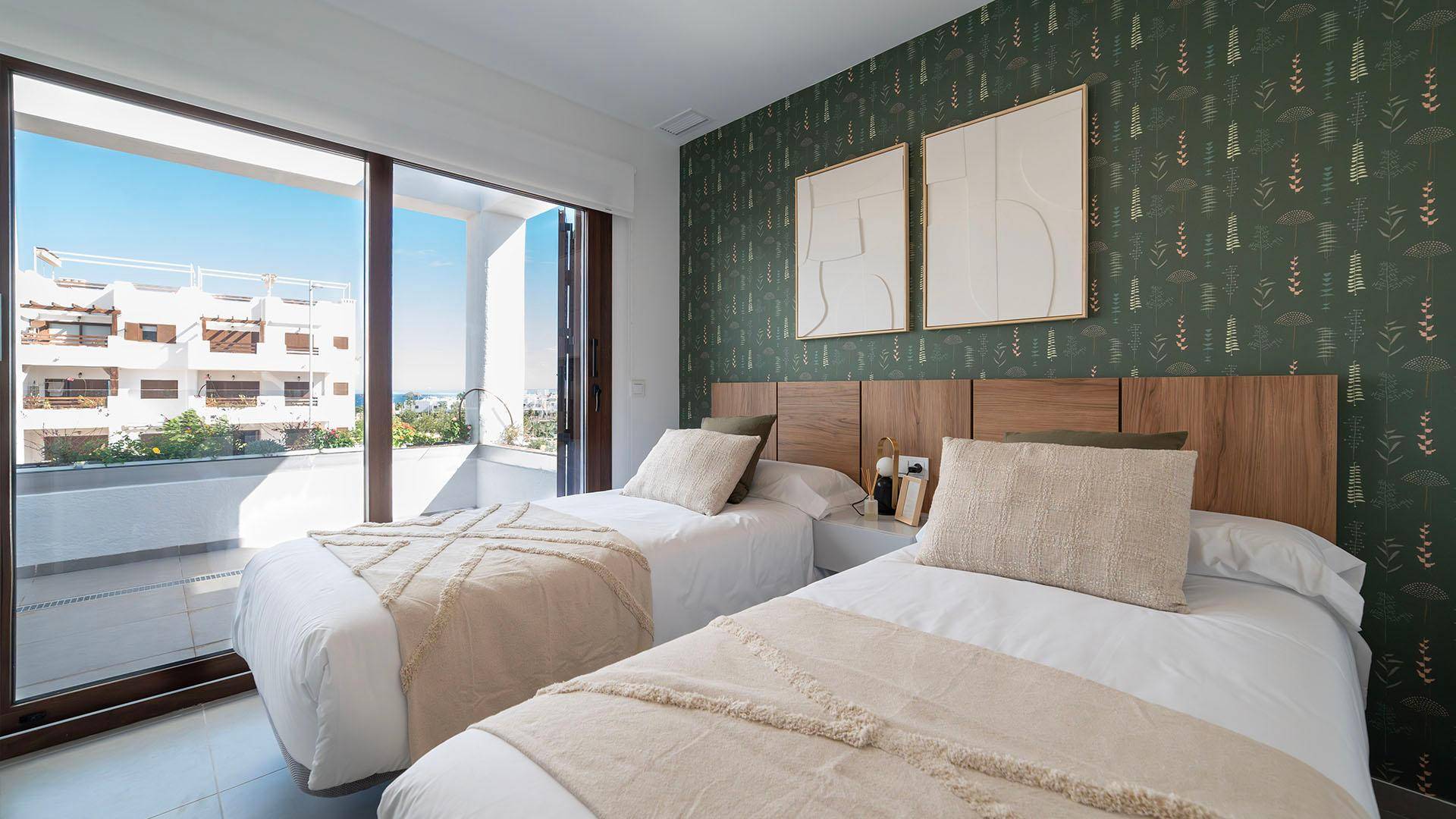 Schlafzimmer mit zwei Einzelbetten, gemusterter Tapete und großen Fenstern mit Ausblick.