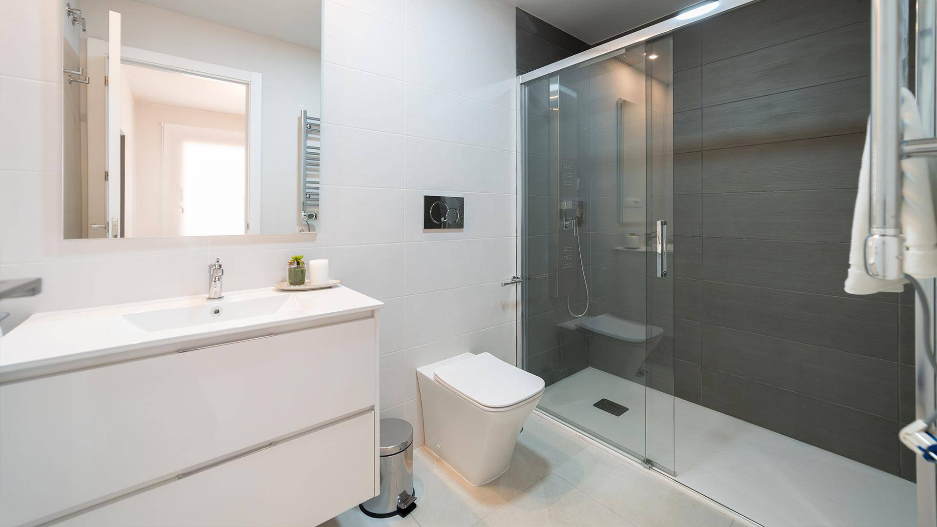 Modernes Badezimmer mit begehbarer Dusche, weißem Waschtisch und beheiztem Handtuchhalter.