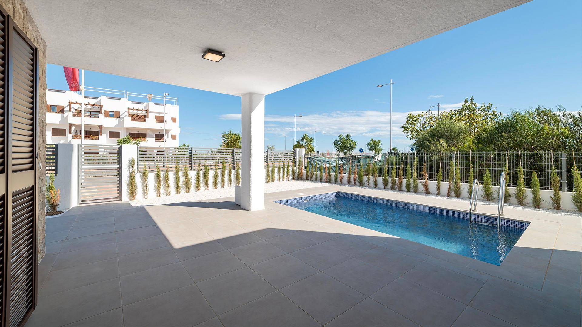 Überdachte Terrasse neben dem Pool mit Blick auf die umliegende Wohnanlage.